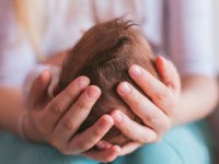Mother holding newborn baby boy on her knees, closeup