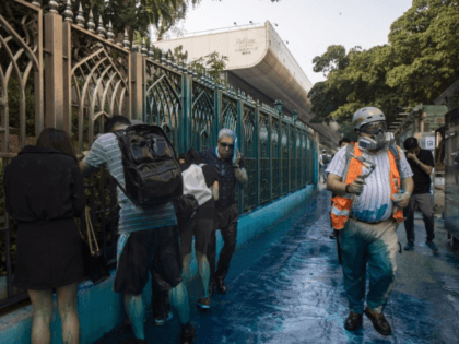 People react after sprayed with blue-dyed water by a police riot-control vehicle during a protest outside the Kowloon Mosque in Hong Kong. Hong Kong officials apologized to leaders of the Kowloon Mosque afterward.(Chan Cheuk Fai /Associated Press)