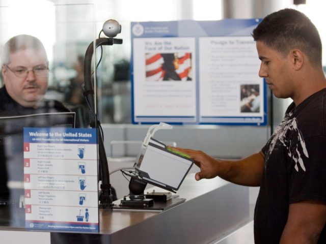 HOUSTON - FEBRUARY 1: U.S. Customs and Border Protection officer Thomas Wuenschel (L) monitors his screen as an arriving passenger uses a new biometric scanner at George H. W. Bush Intercontinental Airport February 1, 2008 in Houston, Texas. The new system is set up to scan all ten fingers instead …