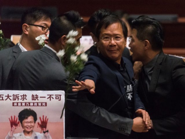 Pro-democracy lawmaker Kwok Ka-ki (C) is escorted by security after throwing flowers insid