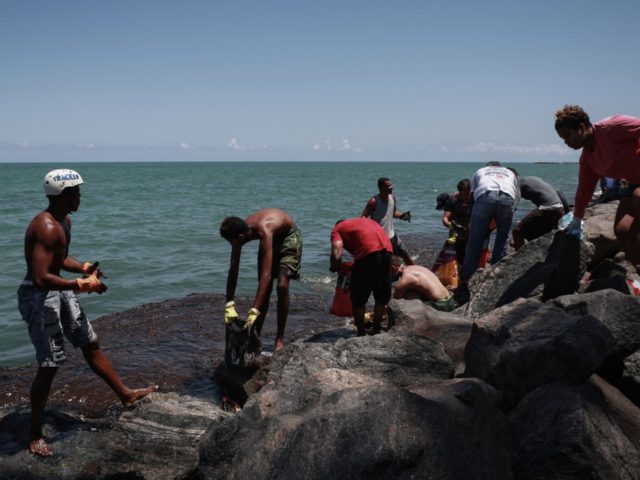 Volunteers remove crude spilled at Janga beach in Paulista, Pernambuco state, Brazil, on October 23, 2019. - Large blobs of oil staining more than 130 beaches in northeastern Brazil began appearing in early September and have now turned up along a 2,000km stretch of the Atlantic coastline. The source of …