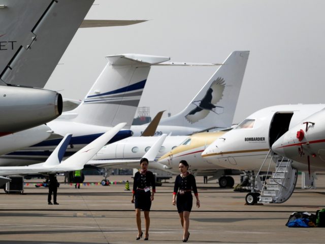 This photo taken on April 11, 2016 shows two crew members walking past business jets ahead of the 2016 Asian Business Aviation Conference and Exhibition (ABACE 2016) at Shanghai Hongqiao Airport in Shanghai. Some of China's wealthier investors are buying private jets to secure a mobile, dollar-denominated hedge against volatile …