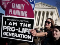 WASHINGTON, DC - JANUARY 19: A pro-life activist tries to block the signs of pro-choice activists in front of the the U.S. Supreme Court during the 2018 March for Life January 19, 2018 in Washington, DC. Activists gathered in the nation's capital for the annual event to mark the anniversary …