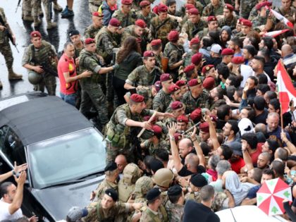 Anti-government protesters facing Lebanese army soldiers wave national flags in the area o