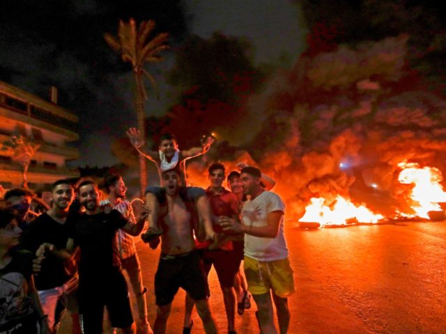Lebanese demonstrators chant slogans in front of a tire fire during a protest against rece