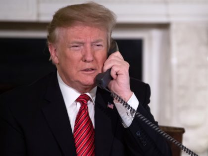 US President Donald Trump speaks on the telephone as he answers calls from people calling