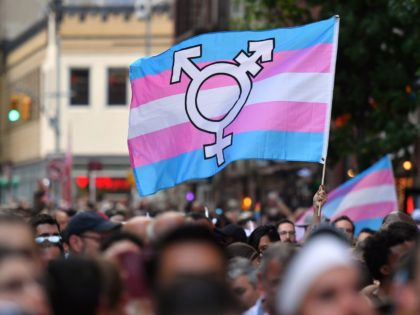 A person holds a transgender pride flag as people gather on Christopher Street outside the