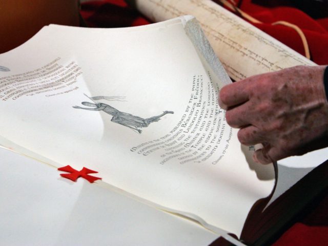 A hand turns pages of a replica document of the trial 700 years ago, in which Pope Clement
