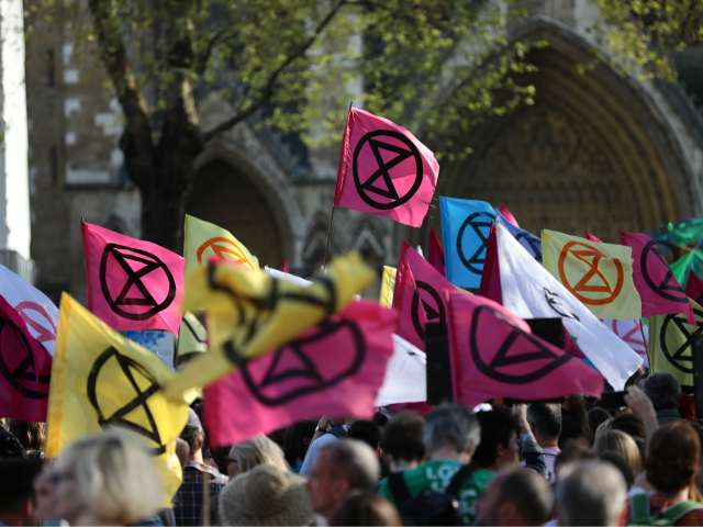 LONDON, ENGLAND - APRIL 21: Extinction Rebellion flags are held aloft as protesters gather at Parliament Square in Westminster as the Extinction Rebellion protests enter their seventh day on April 21, 2019 in London, England. The environmental campaign group has blocked a number of key junctions in central London in …