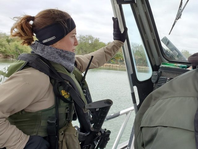 A female riverine Border Patrol agent stands watch during a shift on the Rio Grande. (Phot