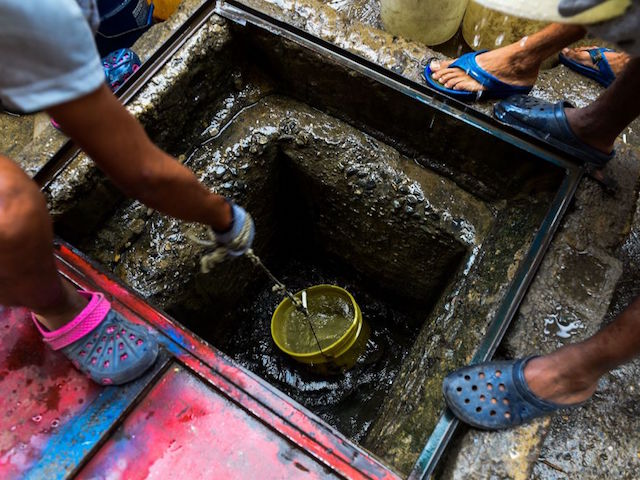 People draw water from a spring water tank to be used in their toilets, at Petare neighborhood in Caracas on April 1, 2019. - Venezuela's President Nicolas Maduro announced 30 days of electricity rationing Sunday, after his government said it was shortening the working day and keeping schools closed due to blackouts. (Photo by Federico Parra / AFP) (Photo credit should read FEDERICO PARRA/AFP via Getty Images)
