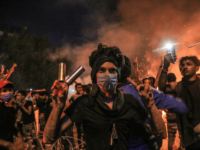 A protester wears tear gas canisters on his fingers and gestures the victory sign during a