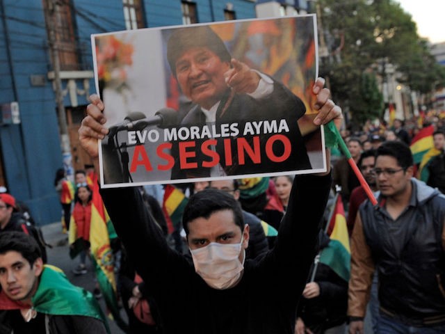 A man holds a sign depicting Bolivian President Evo Morales reading "Assassin" during an open forum summoned by the National Committee in Defense of Democracy (CONADE) on the second week of civic strike against the results of the October 20 election in La Paz on October 31, 2019. - A …