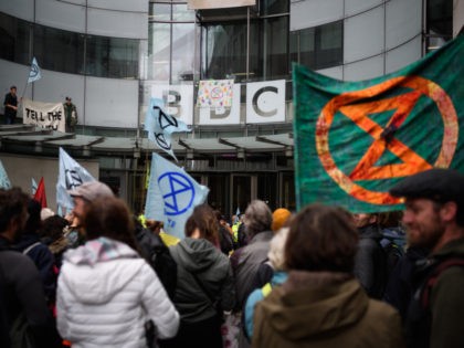 LONDON, ENGLAND - OCTOBER 11: Two men stand on a glass canopy above the entrance as Extinction Rebellion environmental campaigners gather outside the headquarters of the BBC to protest about their alleged silence over climate issues on October 11, 2019 in London, England. The Extinction Rebellion group is in the …