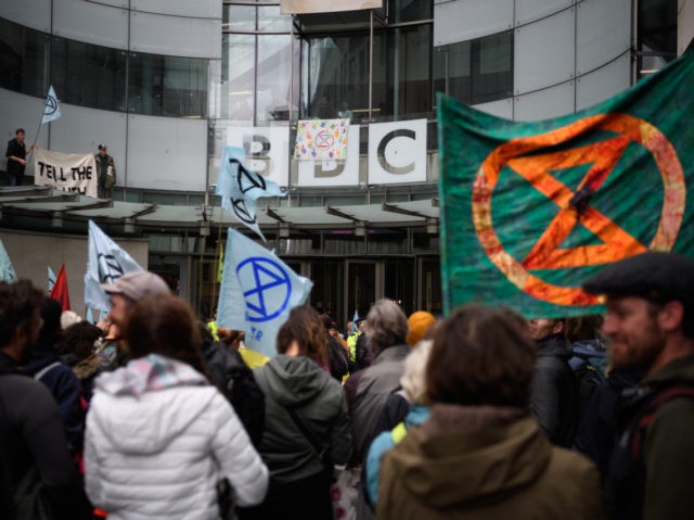 LONDON, ENGLAND - OCTOBER 11: Two men stand on a glass canopy above the entrance as Extinc