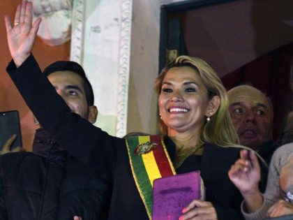 TOPSHOT - Deputy Senate speaker Jeanine Anez, waves from the balcony of the Quemado Palace in La Paz after proclaiming herself the country's new interim president in a session of Congress that failed to reach a quorum, on November 12, 2019. - Bolivia's Evo Morales jetted off to exile in …