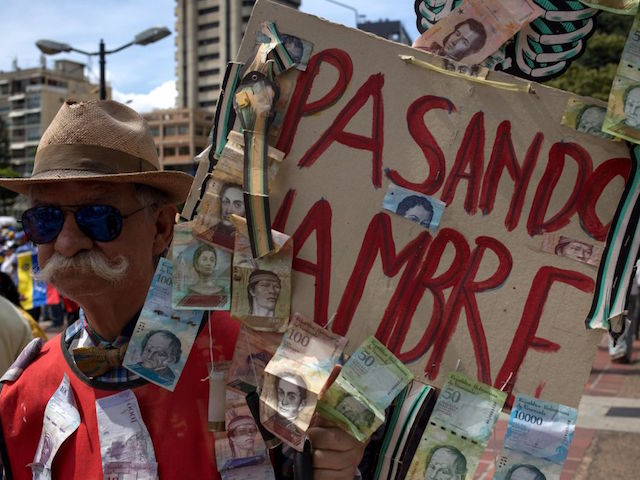 A supporter of Venezuelan opposition leader and self-proclaimed acting president Juan Guaido holds a sign reading "Starving" during a gathering in front of the Bolivian embassy in Caracas on November 16, 2019. - Venezuela's opposition called to protest against President Nicolas Maduroon Saturday, while the government also called on their own supporters to mobilize. (Photo by CRISTIAN HERNANDEZ / AFP) (Photo by CRISTIAN HERNANDEZ/AFP via Getty Images)