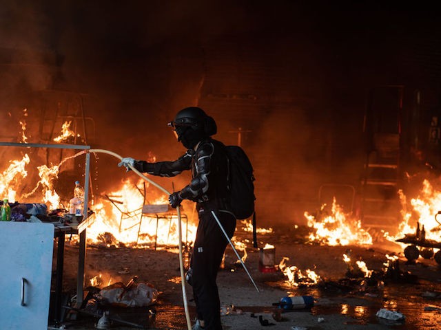 HONG KONG, CHINA - NOVEMBER 18: An anti-government protester puts out a fire at Hong Kong Polytechnic University on November 18, 2019 in Hong Kong, China. Anti-government protesters organized a general strike since Monday as demonstrations in Hong Kong stretched into its sixth month with demands for an independent inquiry into police brutality, the retraction of the word "riot" to describe the rallies, and genuine universal suffrage. (Photo by Laurel Chor/Getty Images)
