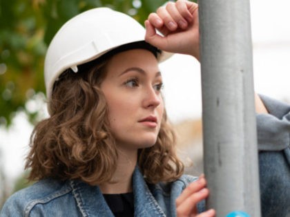 Close up portrait of a pensive and contemplative factory female employee wearing a white protective hard hat