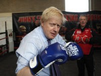 MANCHESTER, ENGLAND - NOVEMBER 19: Britain's Prime Minister Boris Johnson poses for a photo wearing boxing gloves emblazoned with "Get Brexit Done" during a stop in his General Election Campaign trail at Jimmy Egan's Boxing Academy on November 19, 2019 in Manchester, England. Britain goes to the polls on Dec.12. …