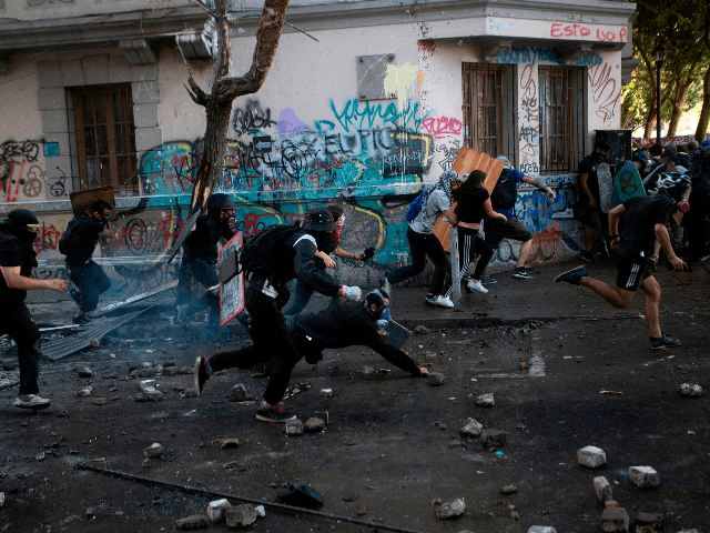 Demonstrators run to escape from riot police during a protest against the government in Santiago on November 19, 2019. - President Sebastian Pinera condemned on Sunday for the first time what he called abuses committed by police in dealing with four weeks of violent unrest that have rocked Chile and …