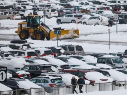 DENVER, CO - NOVEMBER 26: People walk past snow-covered cars parked as a plow clears roadways at Denver International Airport on November 26, 2019 in Denver, Colorado. Flights were delayed and rescheduled due to a winter storm that dropped nearly a foot of snow in the city. (Photo by Joe …