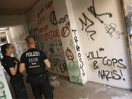 BERLIN, GERMANY - JULY 12: Graffiti, including one scrawl that reads: "Kill Cops and Nazis", covers the entrance to the apartment building at Rigaer Strasse 94 as police stand by on July 12, 2016 in Berlin, Germany. Rigaer Strasse, and especially Rigaer Strasse 94 , have become the focus of …