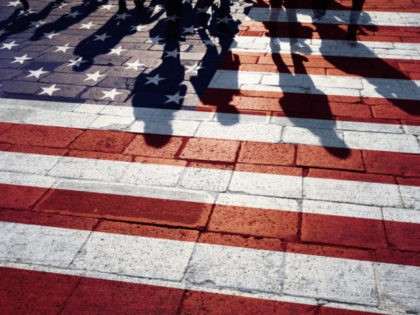 Shadows of group of people walking through the streets with painted Usa flag on the floor. Concept political relations with neighbors.