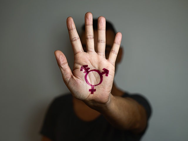 closeup of a transgender symbol painted in the palm of the hand of a young caucasian person