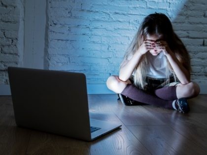 Young girl hides from images on computer. (File Photo: Getty Images)
