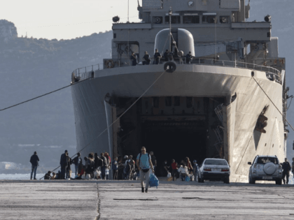 Migrants wait outside a military vessel after their disembarkation at the port of Elefsina, near Athens, on Saturday, Nov. 2, 2019. The transfer of migrants from overcrowded camps on the islands to the Greek mainland continued this weekend, with 415 arriving Saturday afternoon at the port of Elefsina west of …