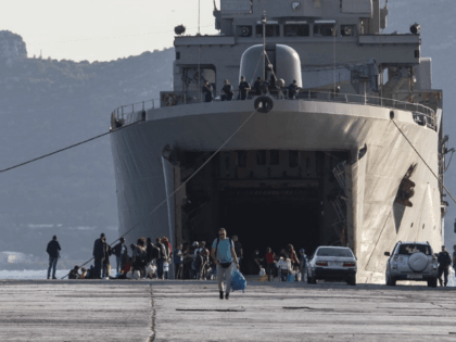 Migrants wait outside a military vessel after their disembarkation at the port of Elefsina