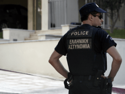 A police officer stands in front of the house of Greek journalist Socratis Guiolas, after the latter was killed, on July 19, 2010 in Athens. Gunmen shot and killed Guiolas, early Monday in front of his home near Athens, before fleeing in a car, police said. At least three unknown …