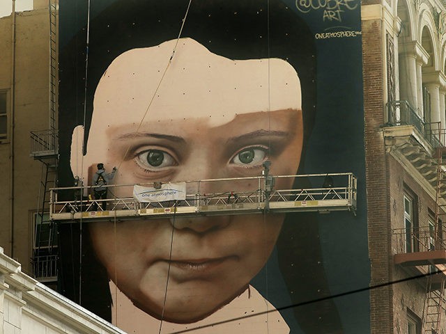 Andres Petreselli paints a mural on the side of a building depicting Swedish teen climate
