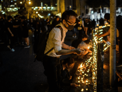 Mourners light candles on a street handrail as they pay their respects outside the carpark where 22-year-old student Alex Chow fell during a recent protest in the Tseung Kwan O district on the Kowloon side of Hong Kong early on November 9, 2019. - Thousands of Hong Kongers held vigils …
