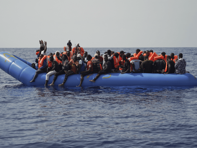 Men aboard a blue plastic boat point to the sky in the Mediterranean Sea, Tuesday, Sept. 1