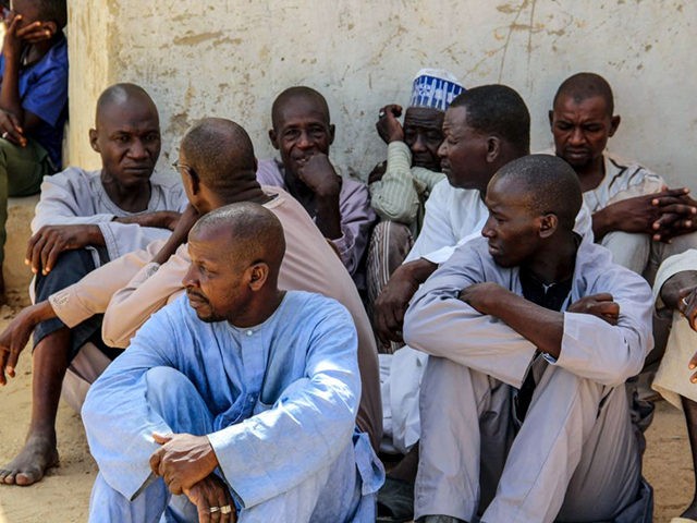 Men gather during a burial ceremony, after two people were killed by Boko Haram fighters i