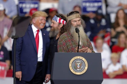 President Donald laughs with Willie Robertson, of the reality TV series Duck Dynasty, and Phil Roberston, the family patriarch, right, at a campaign rally in Monroe, La., Wednesday, Nov. 6, 2019. (AP Photo/Gerald Herbert)