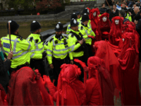 LONDON, ENGLAND - OCTOBER 07: The Red Brigade of The Invisible Circus gesture to police in Westminster on October 7, 2019 in London, England. Climate change activists are gathering to block access to various government departments as they start a two week protest in central London (Photo by Chris J …