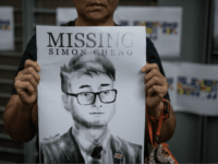 HONG KONG, CHINA - AUGUST 21: A woman holds a poster showing a portrait of British consulate worker Simon Cheung, who was detained 14 days ago by Chinese officials during a gathering to petition the British government to assist in the his release, outside the British Consulate on August 21, …