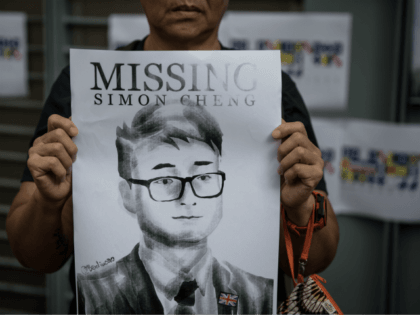 HONG KONG, CHINA - AUGUST 21: A woman holds a poster showing a portrait of British consulate worker Simon Cheung, who was detained 14 days ago by Chinese officials during a gathering to petition the British government to assist in the his release, outside the British Consulate on August 21, …