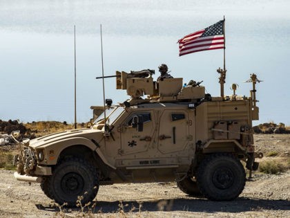 A US soldier sits atop a military vehicle, part of a joint convoy with the Kurdish People's Protection Units (YPG) (unseen) patrolling near the town of Al-Muabbadah in the northeastern Syrian Hasakeh province on the border with Turkey, on November 9, 2019. (Photo by Delil SOULEIMAN / AFP) (Photo by …