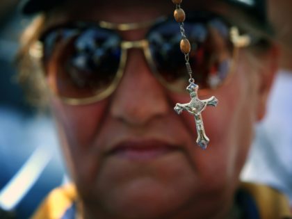 An Iraqi woman holds up a cross during a demonstration against the threat imposed by the I