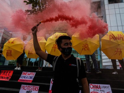 Activists holding umbrellas in support of pro-democracy protesters in Hong Kong stand in f