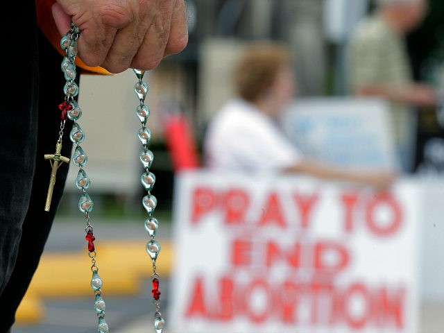 Phil Thiltrickett, an opponent of an abortion, holds a rosary as he prays outside a Planne