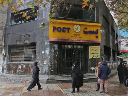 Iranians gather outside a post office branch that was damaged during demonstrations agains