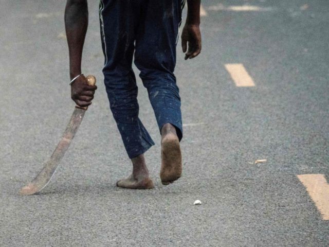 A supporter of National Super Alliance (NASA) holding a machete reacts towards police offi