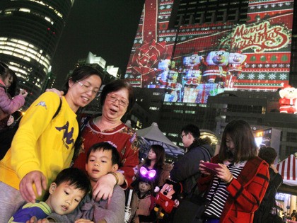 People check their selfie photos in front of Christmas decorations in New Taipei City, Taiwan, Friday, Dec. 23, 2016. (AP photo/Chiang Ying-ying)