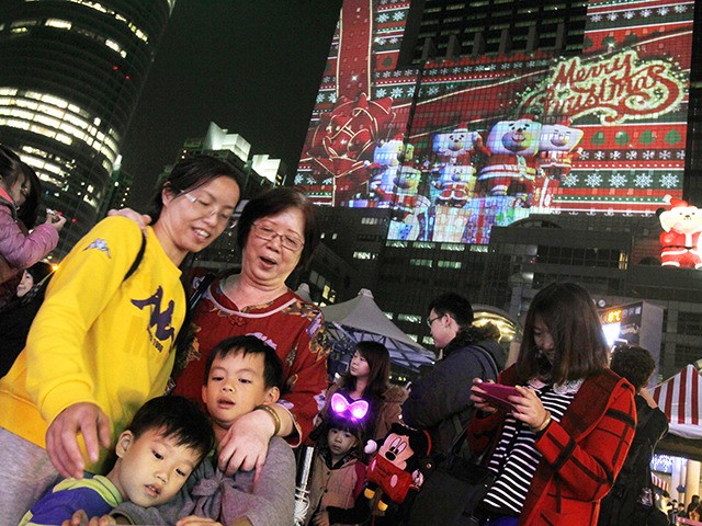 People check their selfie photos in front of Christmas decorations in New Taipei City, Tai