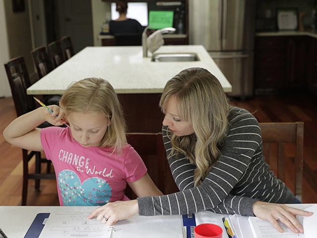 In this Oct. 9, 2019 photo, Donya Grant, right, works on a homeschool lesson with her daughter Mabry, 8, in their home in Monroe, Wash. The family joined a lawsuit against the Monroe School District and others, alleging that the district failed to adequately respond to PCBs, or polychlorinated biphenyls, …